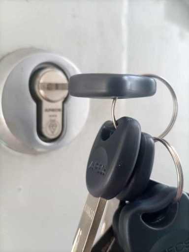 A set of keys inserted into a silver door lock.